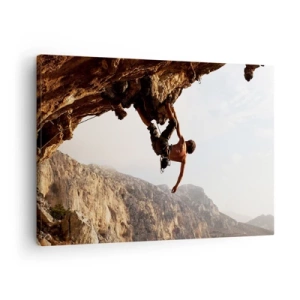 Vászonkép - Egy hegymászó egy meredek sziklán a hegyekben a napsütésben - 70x50cm - A világ egy szikladarabon összezsugorodott egy kézben  - Modern fali dekoráció nappalihoz és hálószobához ARTTOR