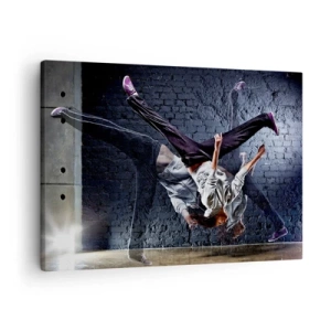 Vászonkép - Egy táncos dinamikus ugrásban egy téglafalnak - 70x50cm - Utcai sztár - Modern fali dekoráció nappalihoz és hálószobához ARTTOR