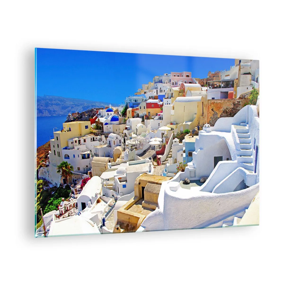 Üveg kép - Santorini fehér házakkal a kék ég előtt - 70x50cm - Álom a görög nyárról - Modern fali dekoráció nappalihoz és hálószobához ARTTOR