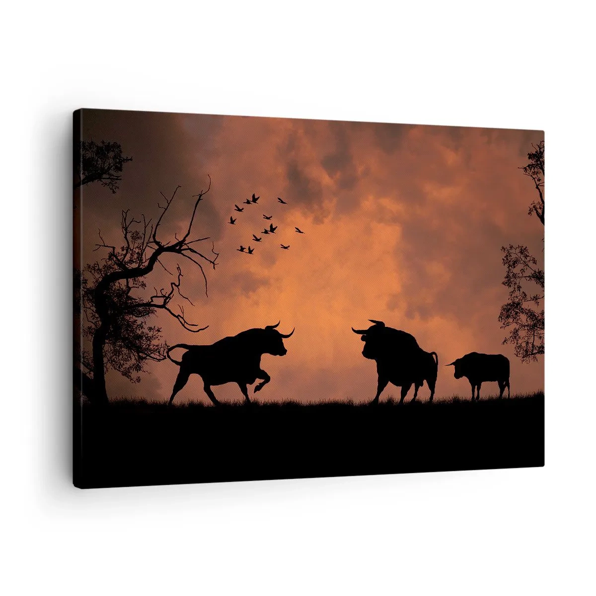 Vászonkép - Bikák sziluettjei narancssárga égbolton naplementekor - 70x50cm - A természet drámai előadása - Modern fali dekoráció nappalihoz és hálószobához ARTTOR