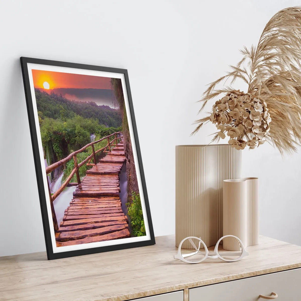 Poszter fehér keretben - Egy fahíd a zöld növényzet és a lenyugvó nap között - 50x70cm - Hihetetlen szépség - Modern fali dekoráció nappalihoz és hálószobához ARTTOR
