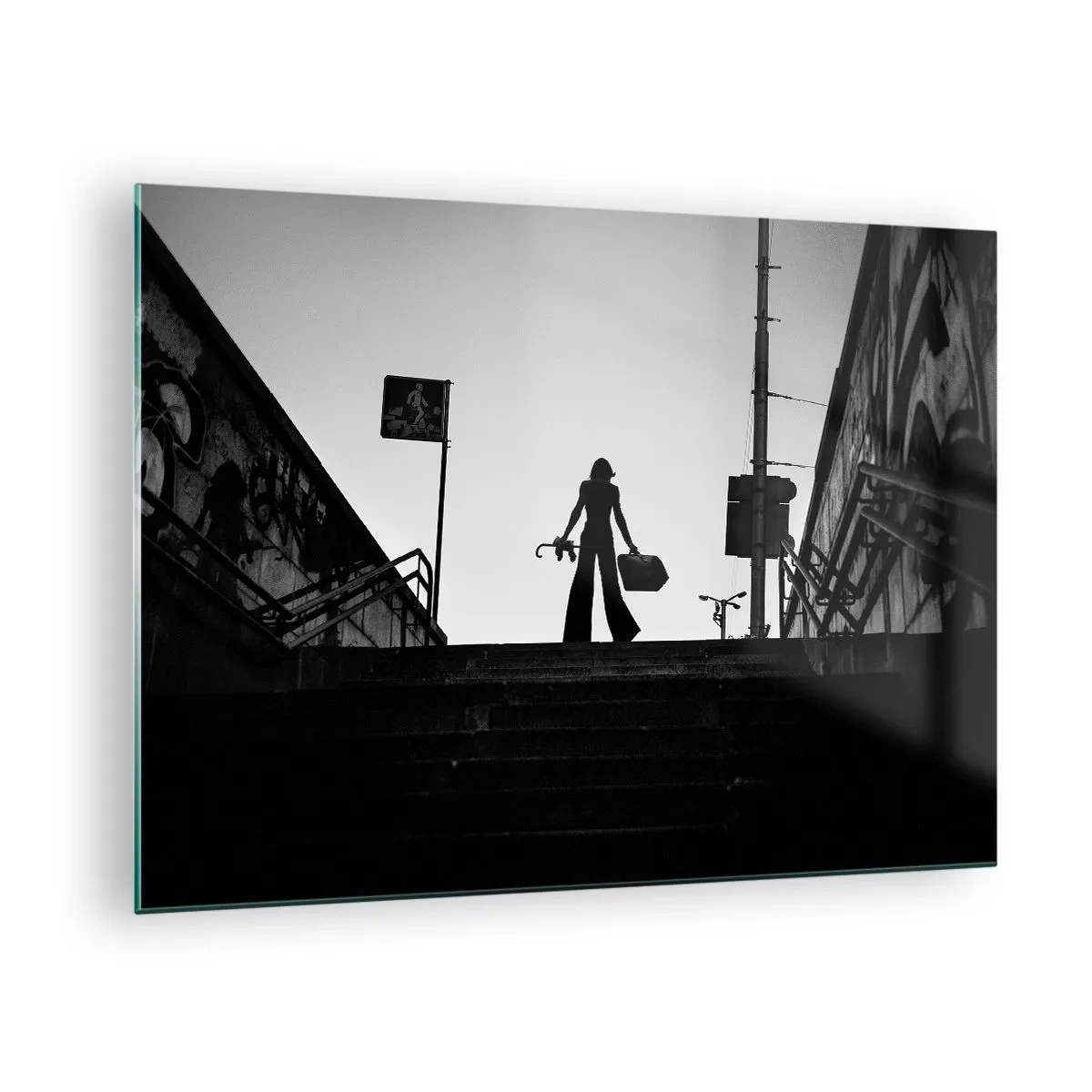 Üveg kép - Fekete-fehér sziluettje egy nőnek a városkép hátterében - 70x50cm - Városi vándorlás - Modern fali dekoráció nappalihoz és hálószobához ARTTOR