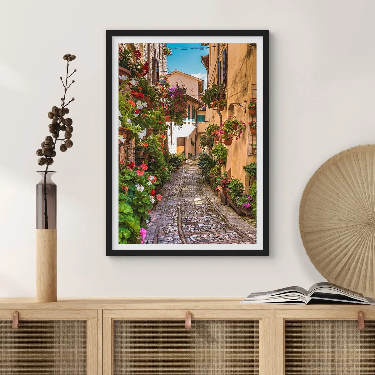 Poszter fehér keretben - Egy bájos utca virágokkal és macskaköves ösvénynel egy napsütéses napon - 50x70cm - Olasz sikátor - Modern fali dekoráció nappalihoz és hálószobához ARTTOR