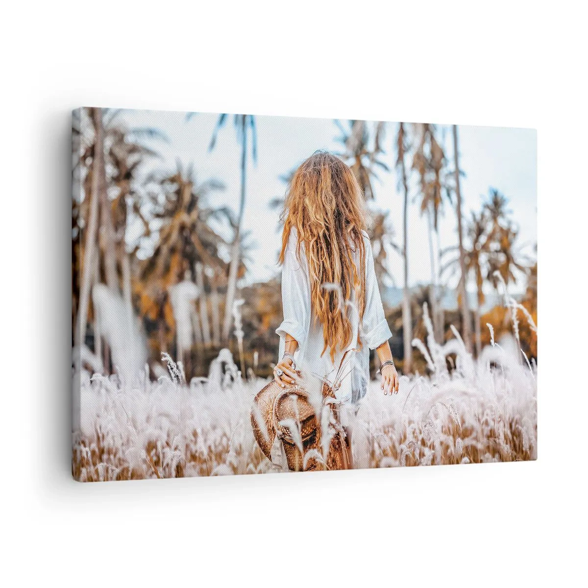 Vászonkép - Egy nő egy füves területen, pálmafákkal a háttérben naplementekor - 70x50cm - Fűbolyhból született - Modern fali dekoráció nappalihoz és hálószobához ARTTOR