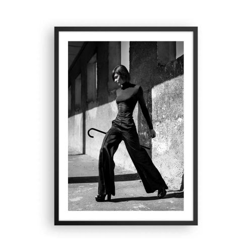 Poszter fehér keretben - Egy elegáns ruhás nő bottal a szigorú építészet hátterében - 50x70cm -   Városi elegancia - Modern fali dekoráció nappalihoz és hálószobához ARTTOR