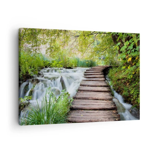 Vászonkép - Egy fahíd egy vízesés felett, buja zöld erdővel körülvéve. - 70x50cm - A víz egyáltalán nem csendes - Modern fali dekoráció nappalihoz és hálószobához ARTTOR